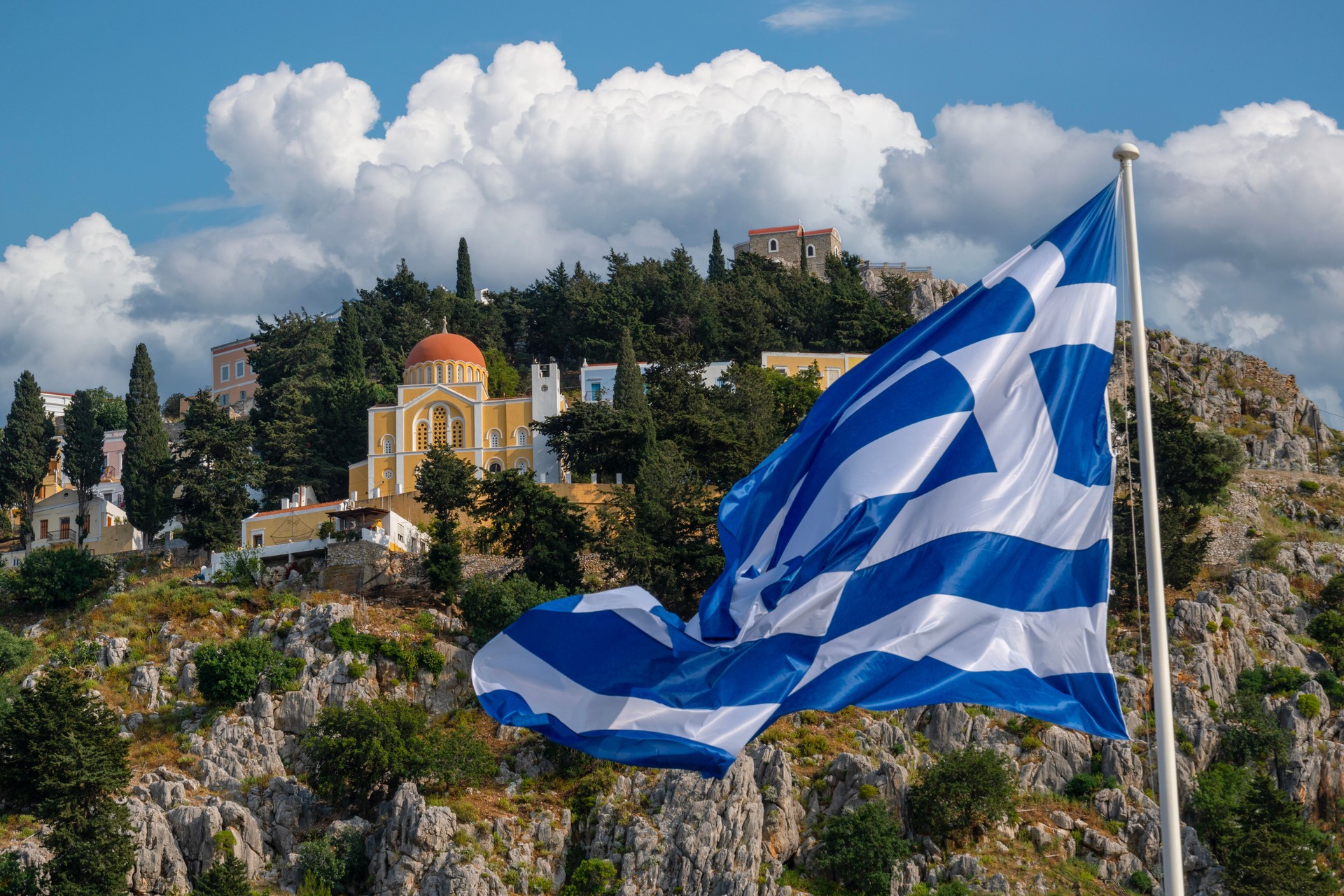 Church and waving Greek flag on the Greek island of Symi.